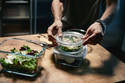 A man using three IKEA 365+ food containers to prepare lunch boxes.