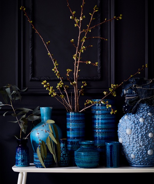 A collection of blue vases on a white bench.