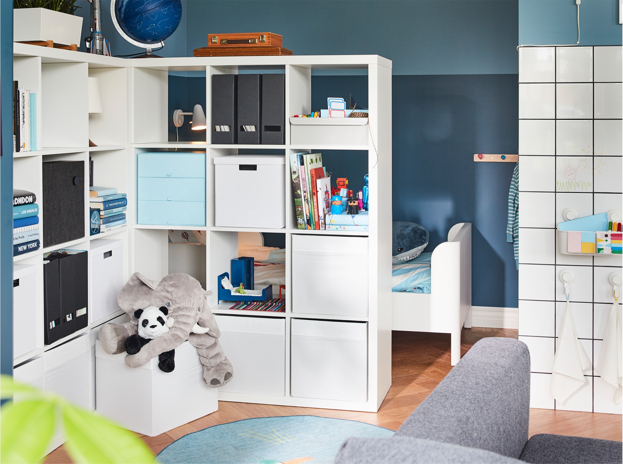  Two shelving units serve as a room divider while offering much storage space. Behind them, you can glimpse a children's bed.