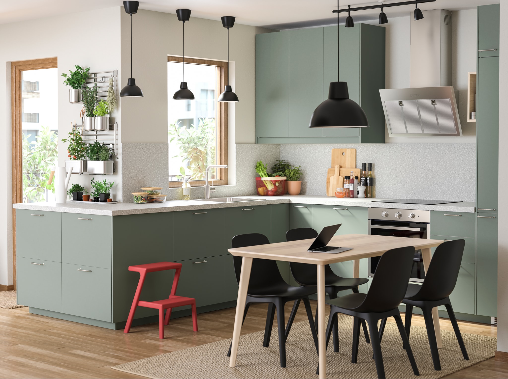  A grey-green kitchen, a wooden dining table, black chairs, a black pendant lamp and lots of herbs that hang on rails.