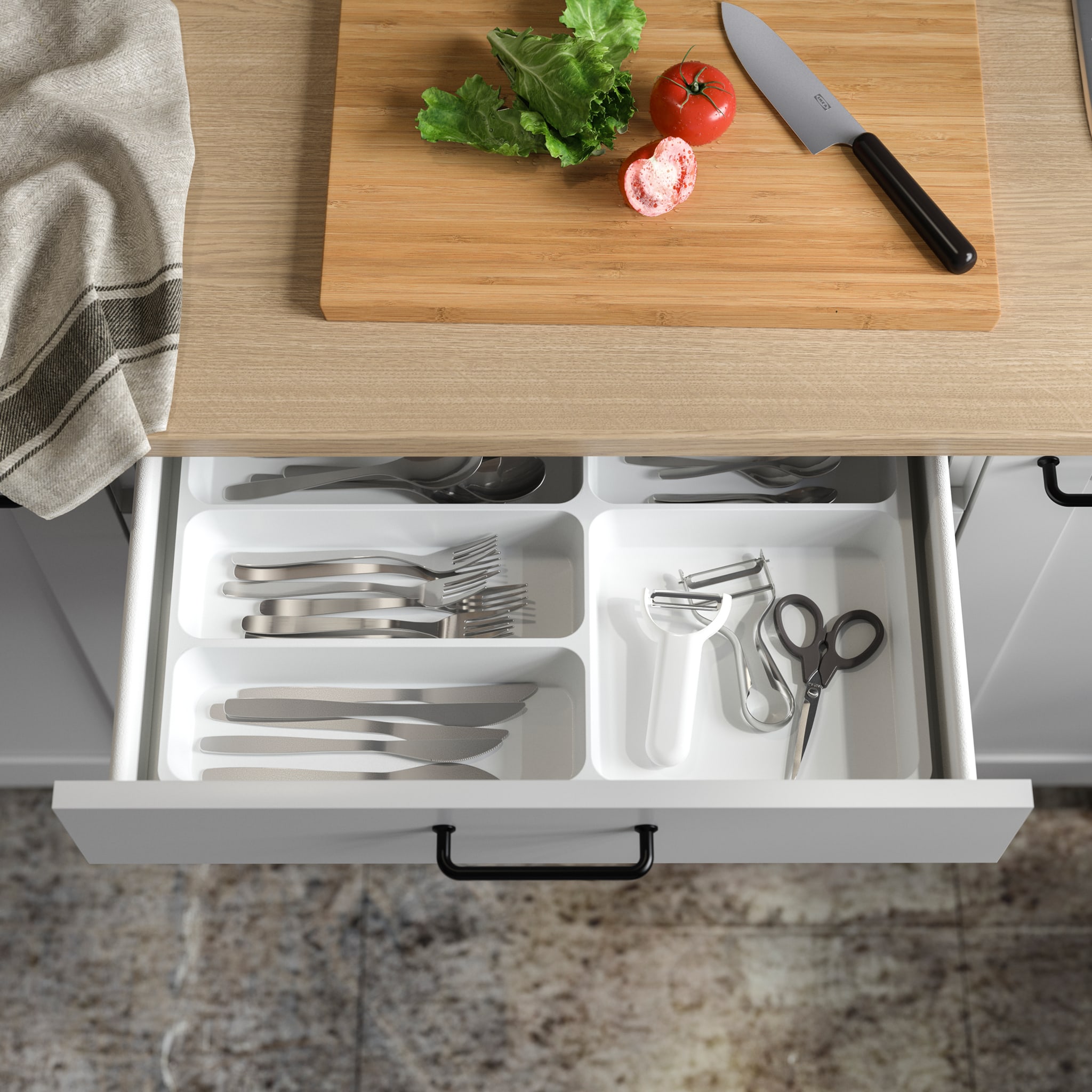  A white cutlery tray is placed inside an open kitchen drawer and shows divided and organised cutlery and more.