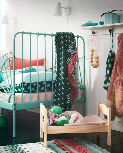 A DUKTIG doll’s bed in solid pine with bed linen and soft toys is standing next to a children’s bed in turquoise.