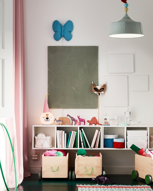 A white, wall-mounted shelf unit. Toys, books, baskets and a table lamp stand on the shelves and the top surface.