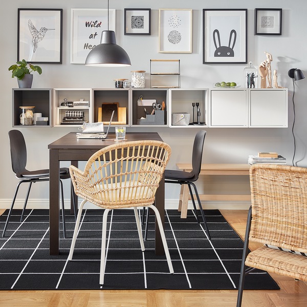 An EKET combination with both open and closed cabinets in grey and white is wall-mounted by a brown table.