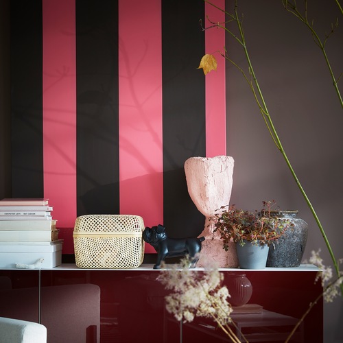 A SMARRA box with lid in bamboo offers storage and it’s standing on a white/red-brown cabinet amongst other decorative items.