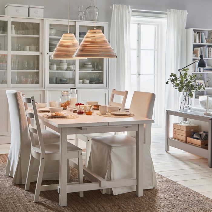 NORDVIKEN extendable table and chairs stand in a breakfast setting. Lit pendant lamps give warm lighting from above.