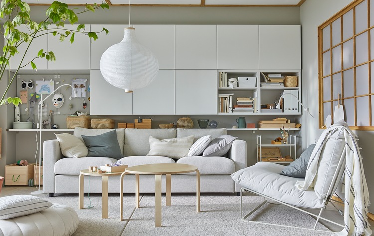 A bright living room with a HAVSTA easy chair, many white wall-mounted cabinets and a round, white pendant lamp.