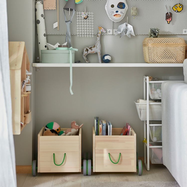 Two FLISAT toy storage units in solid pine with grey wheels and green handles store children’s books and more.