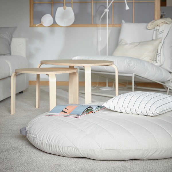 A DIHULT pouffe with handle is lying on a living room rug, and it offers a comfy and spacious seat for children.