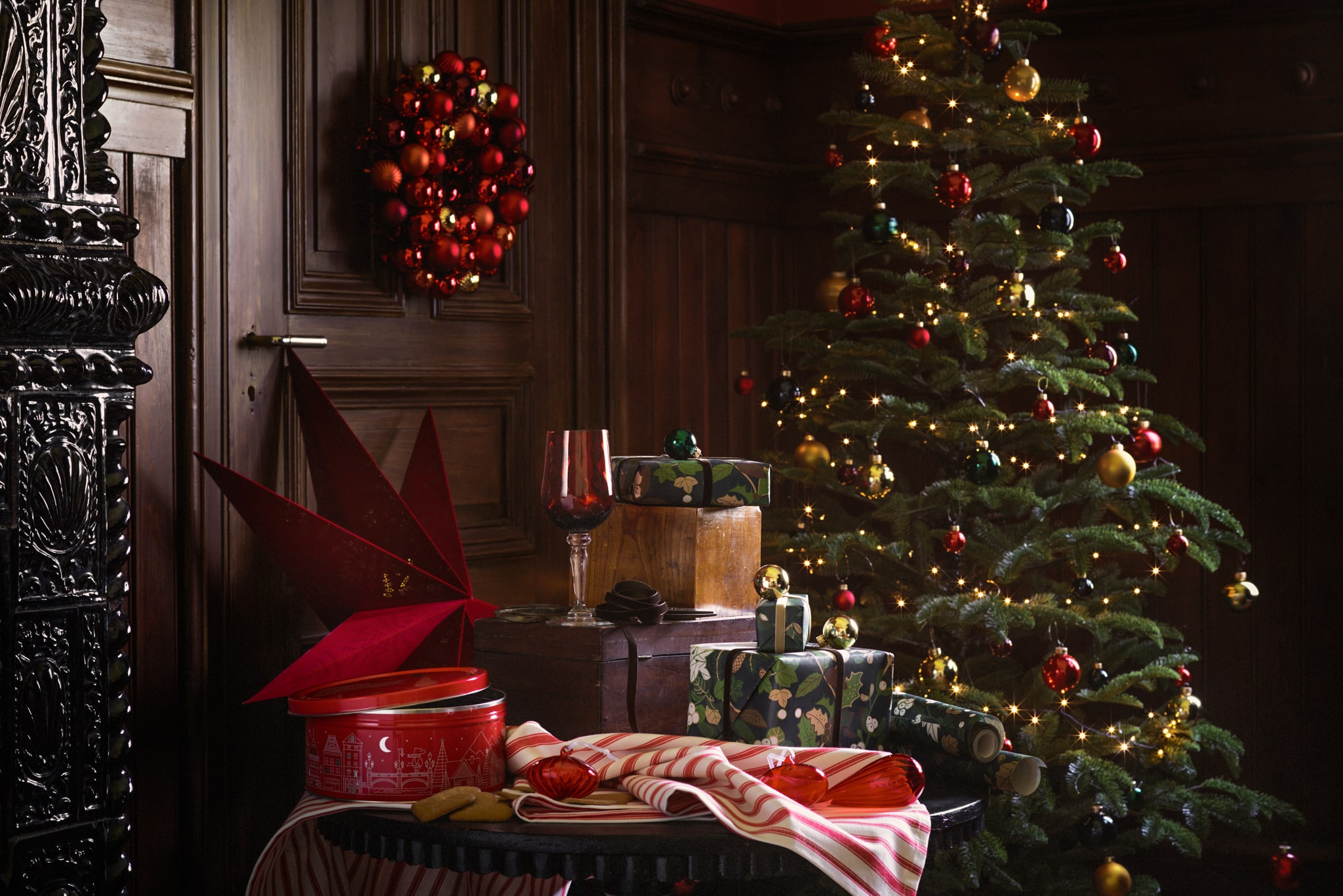 A selection of products stand in a wood-panelled room, including a Christmas tree, gift wrap and home accessories.