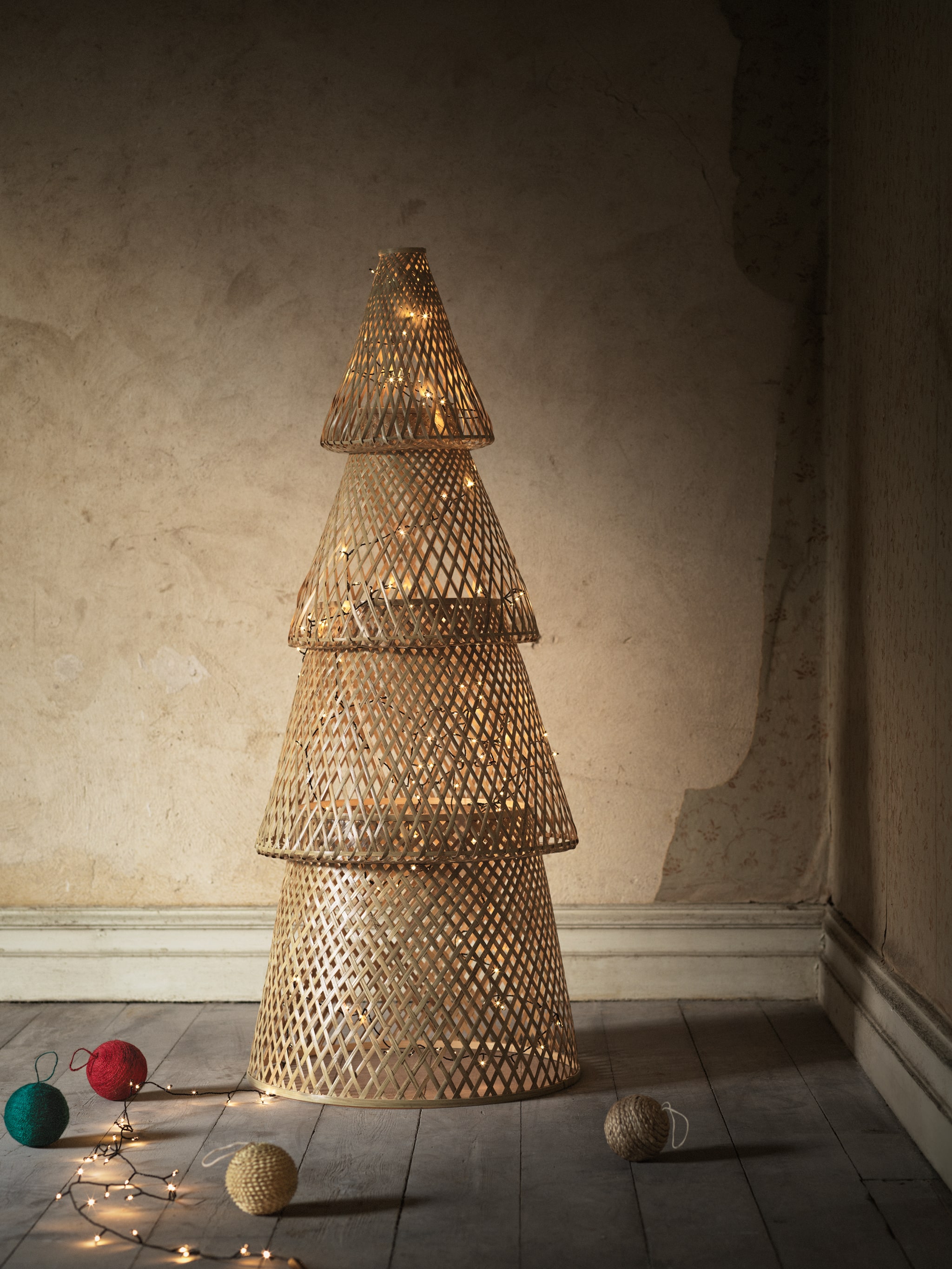 A VINTER 2020 Christmas tree made of bamboo shapes stands in a living room, lit up by a chain of Christmas lights.