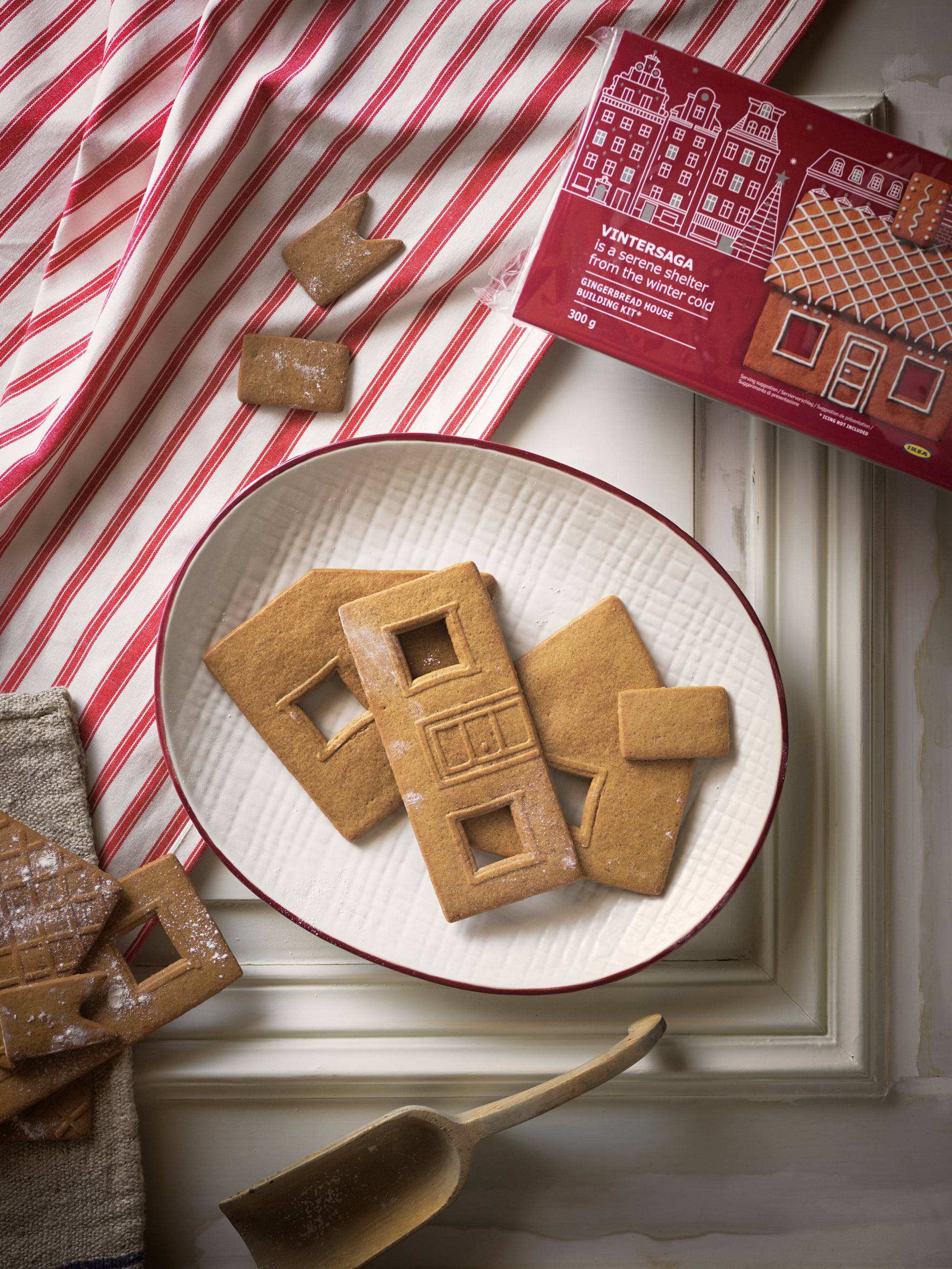 A selection of VINTERSAGA gingerbread house pieces placed on a white VINTER 2020 plate with red rimmed edges.